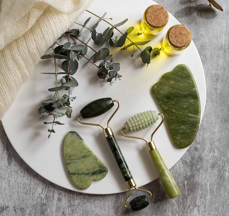 Jade-Roller und Gua Sha Tools auf weißem Teller